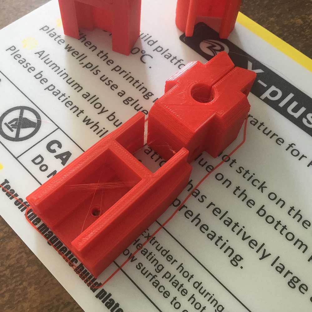 The two parts of the guide scope adapter on the QIDI printer hotbed